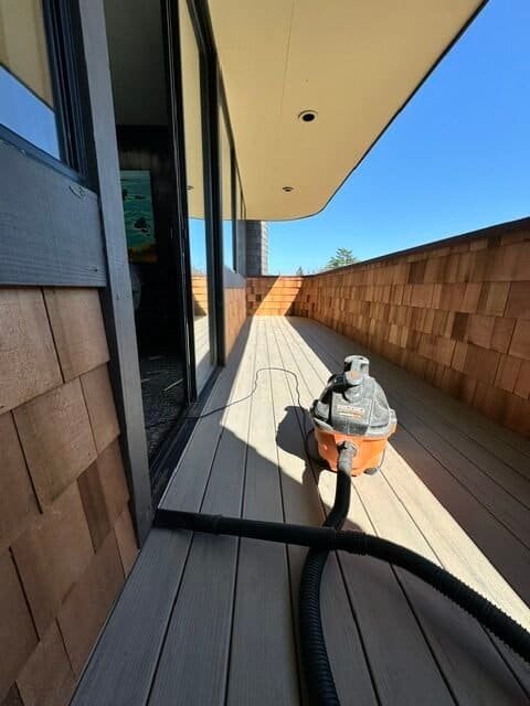 Balcony cleaning with vacuum cleaner on wooden deck.