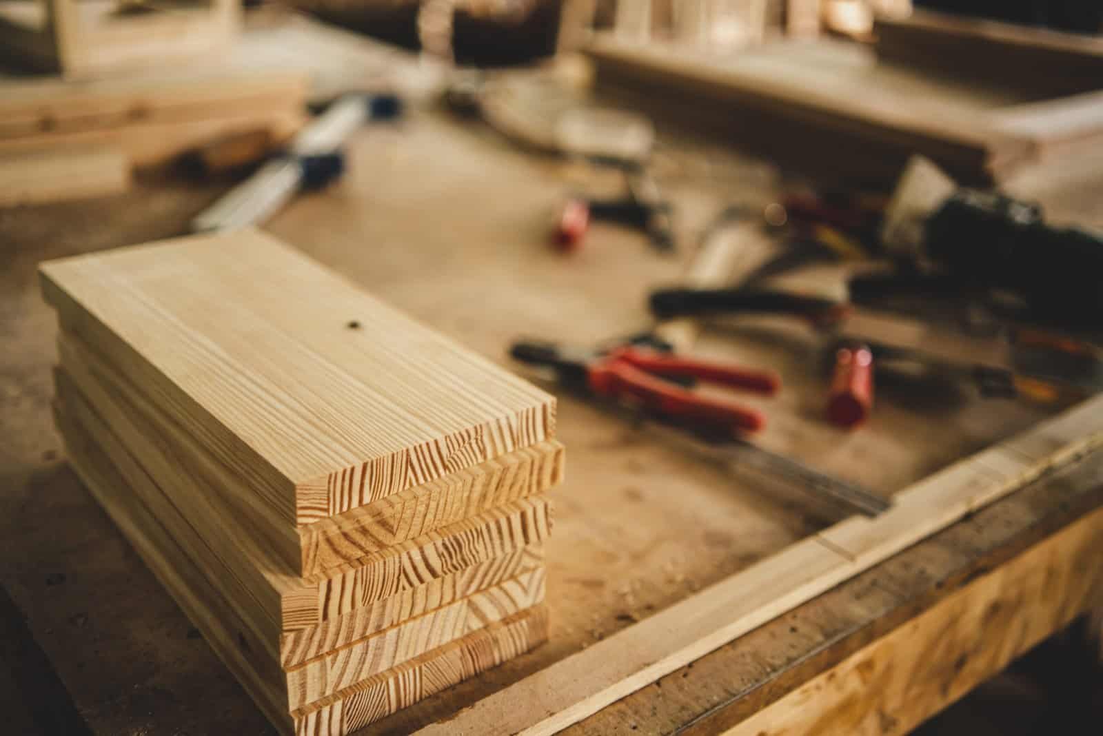 Stacked wooden planks on a workbench in a carpentry workshop.